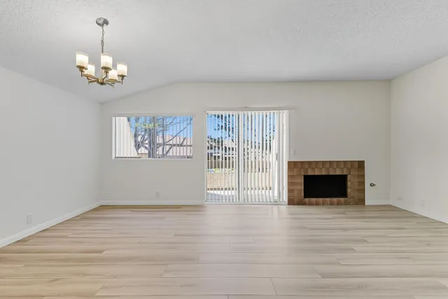 a view of an empty room with wooden floor fireplace and a window