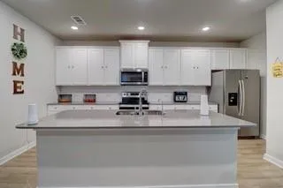 a kitchen with stainless steel appliances granite countertop a refrigerator a stove a sink a microwave and white cabinets