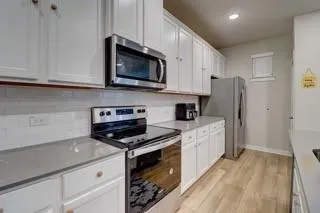 a kitchen with stainless steel appliances granite countertop a refrigerator stove a sink and dishwasher with wooden floor