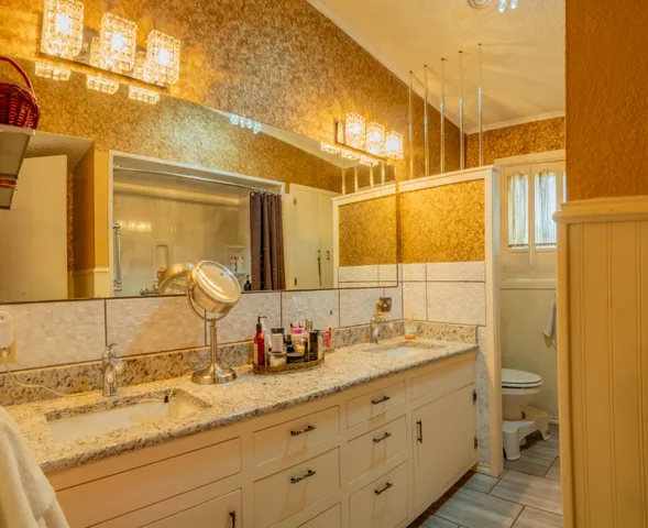 a bathroom with a granite countertop sink vanity mirror and toilet