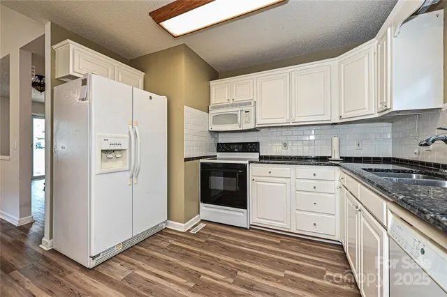 a kitchen with stainless steel appliances granite countertop a refrigerator sink and white cabinets