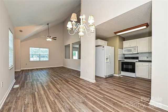a view of a hallway with wooden floor and a kitchen