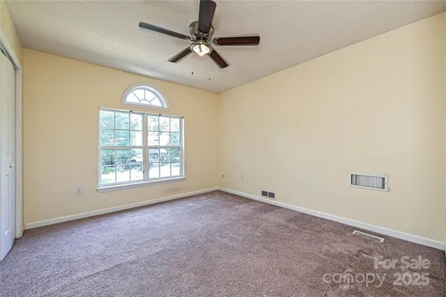 an empty room with windows and fan