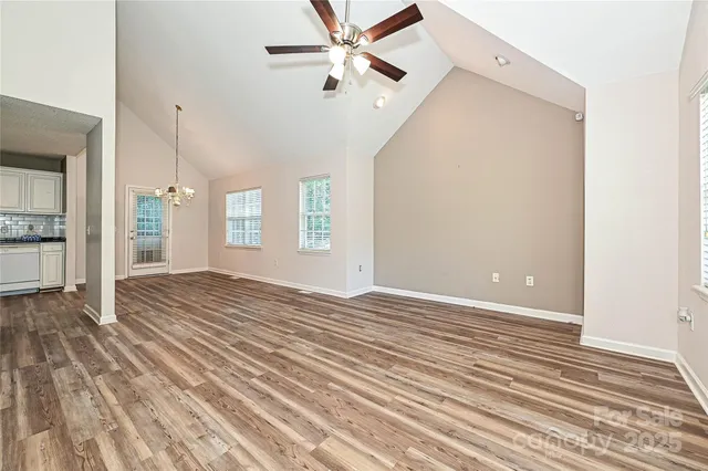 an empty room with wooden floor fan and windows