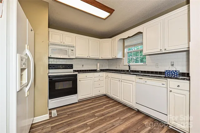 a kitchen with granite countertop white cabinets and white appliances