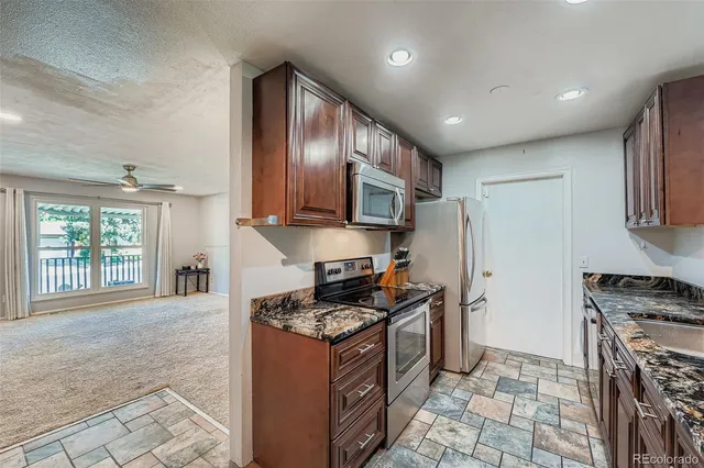a kitchen with stainless steel appliances granite countertop a stove top oven a sink a counter space and cabinets