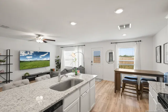 a kitchen with granite countertop a sink and a stove top oven with wooden floor