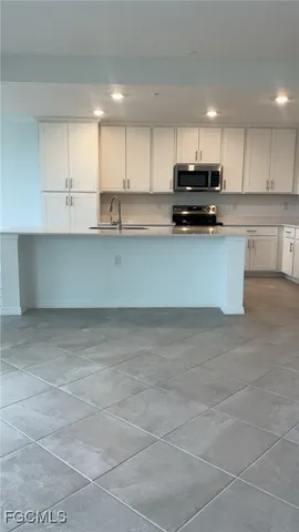 a kitchen with a sink a counter top space stainless steel appliances and cabinets