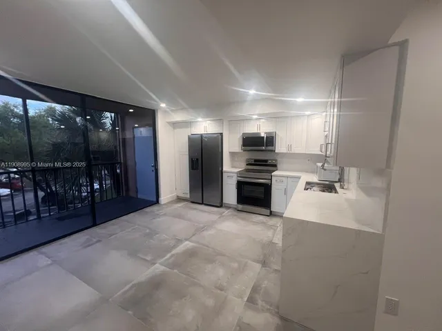 a large white kitchen with a sink stainless steel appliances and cabinets