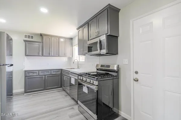 a kitchen with stainless steel appliances granite countertop a refrigerator a stove and a sink with wooden floor