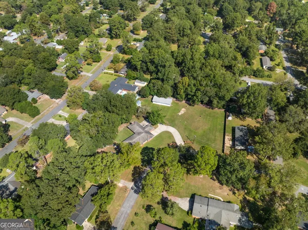 an aerial view of residential houses with outdoor space and trees all around