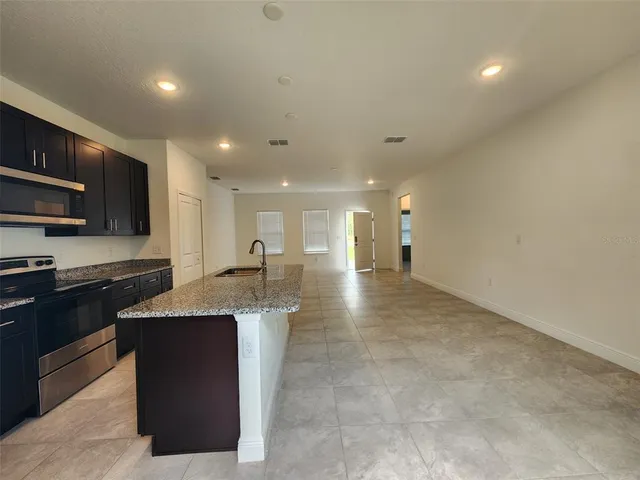 a large kitchen with stainless steel appliances granite countertop a large counter top and a stove top oven