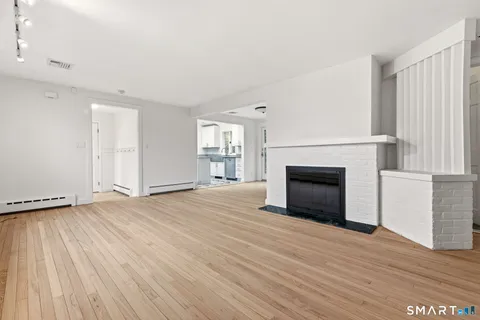 a view of empty room with wooden floor and fireplace