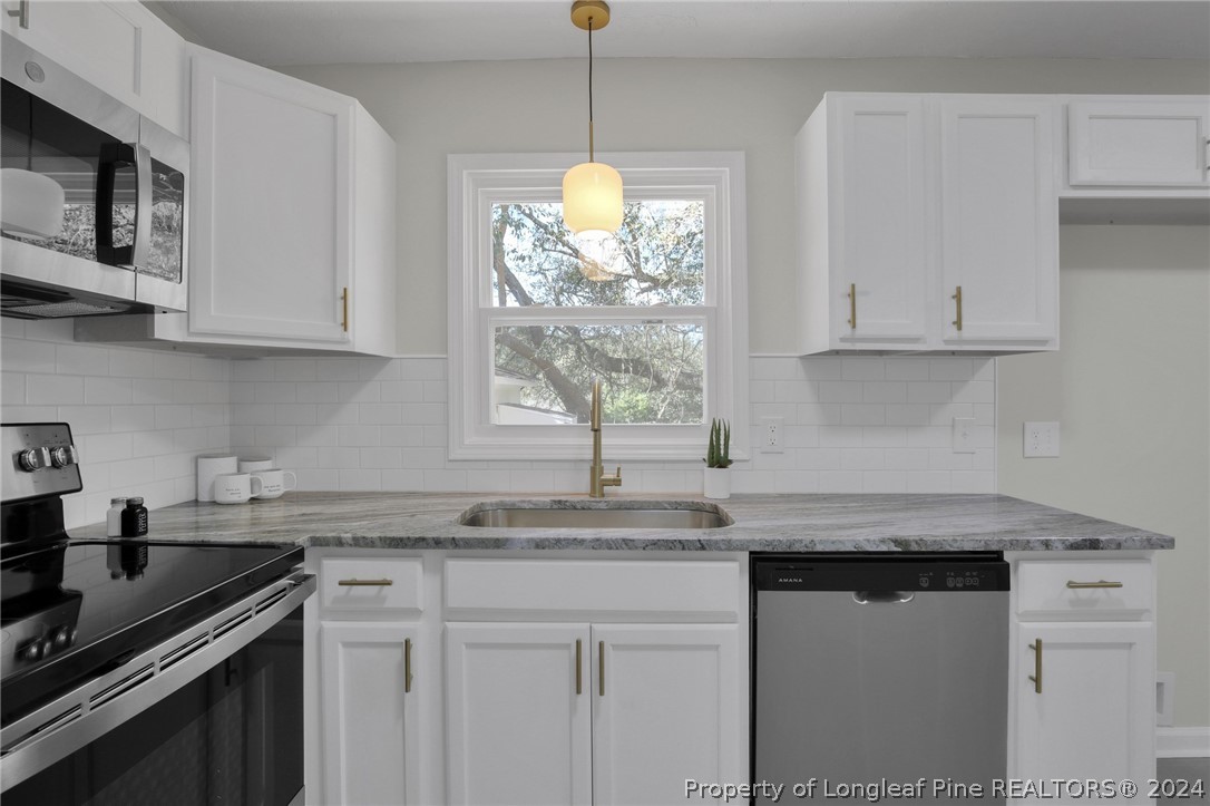 2714 George Owen Road Fayetteville, NC 28306 - Photo 6 of 12 a kitchen with granite countertop a sink stainless steel appliances white cabinets and a window