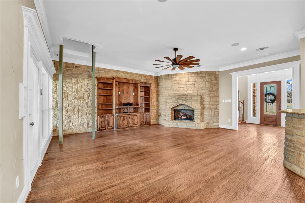 116 McClintock Court Weatherford, TX 76088 - Photo 38 of 38 living room featuring a stone fireplace, wood finished floors, a ceiling fan, and ornamental molding