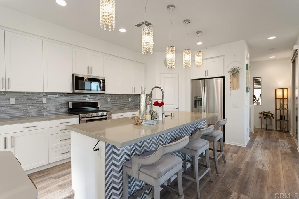 1267 Via Lucero Oceanside, CA 92056 - Photo 12 of 44 a kitchen with stainless steel appliances granite countertop a dining table chairs refrigerator and microwave