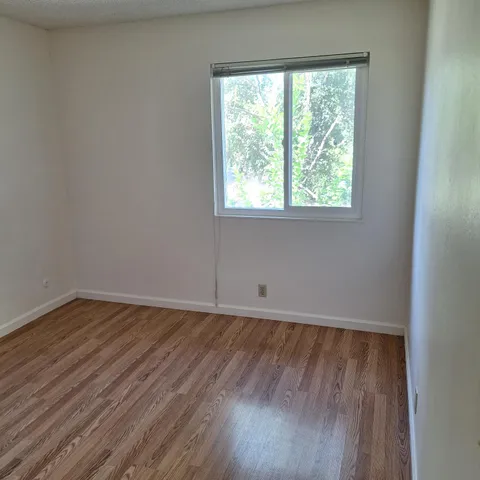an empty room with wooden floor and window