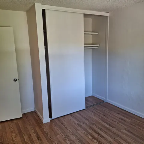 a view of empty room with wooden floor and fan