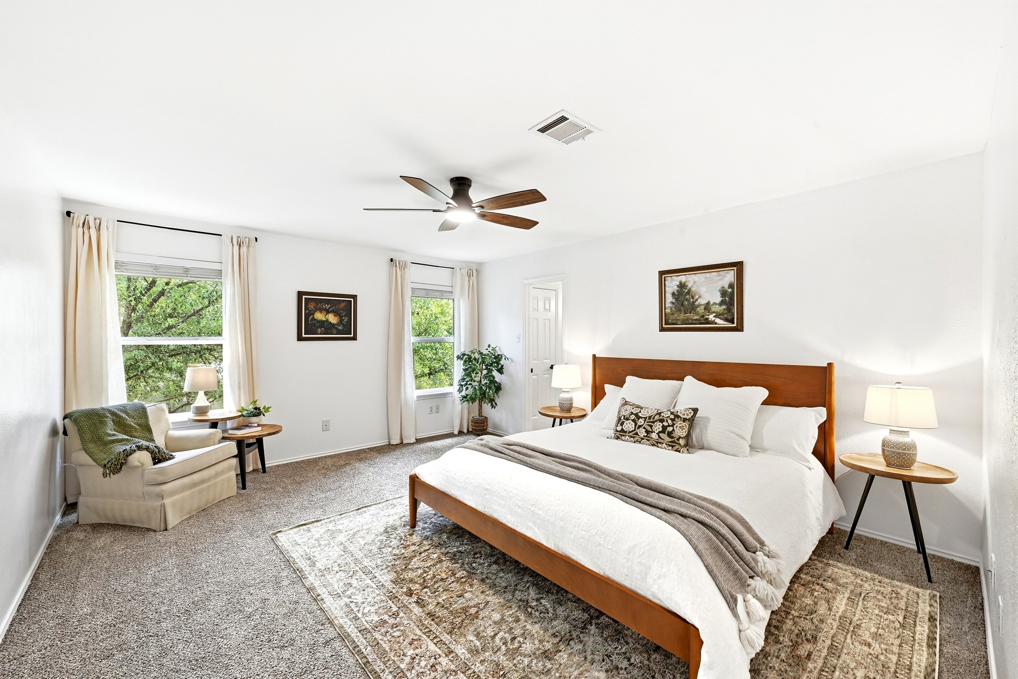 1801 Monks Tale Court Austin, TX 78748 - Photo 16 of 36 Relax in this well-lit primary bedroom featuring a ceiling fan, plush carpeting, and multiple windows overlooking lush greenery.