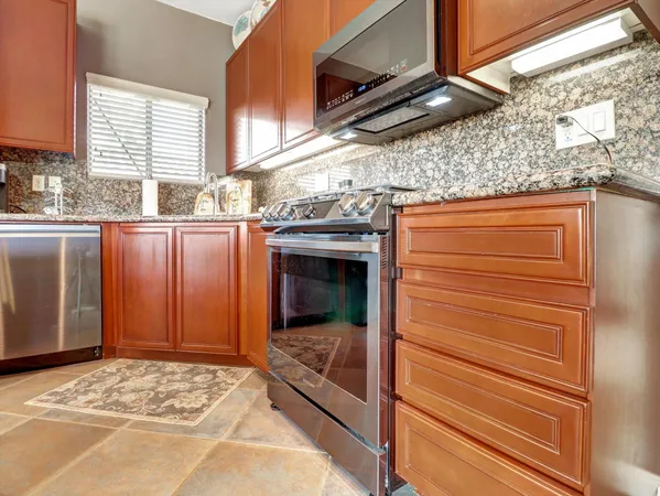 a kitchen with stainless steel appliances granite countertop a sink stove and refrigerator