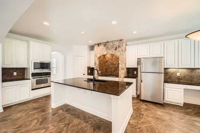 a kitchen with stainless steel appliances granite countertop a refrigerator a stove a sink and a oven