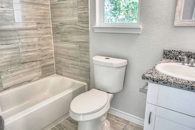 a bathroom with a granite countertop toilet a sink and bathtub