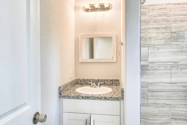 a bathroom with a granite countertop sink and a mirror