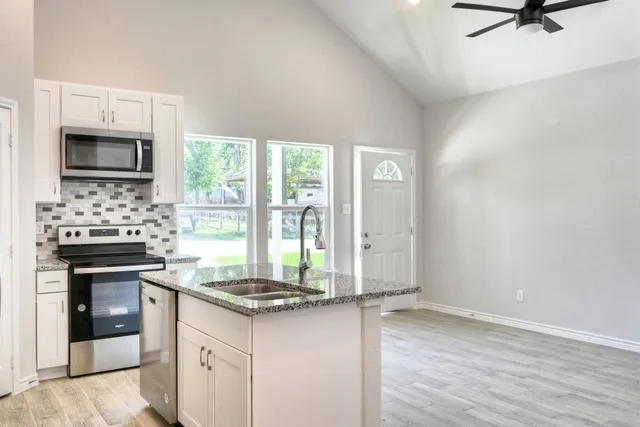 a kitchen with granite countertop a stove a sink and a refrigerator