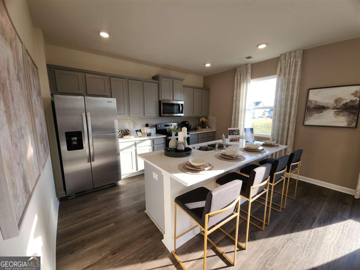 191 Aster Avenue Locust Grove, GA 30248 - Photo 8 of 28 a kitchen with stainless steel appliances a table chairs refrigerator and a sink