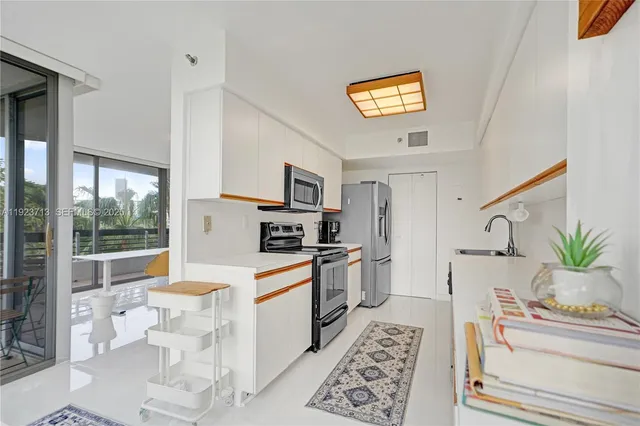 a large white kitchen with stainless steel appliances a stove a sink dishwasher and white cabinets with wooden floor
