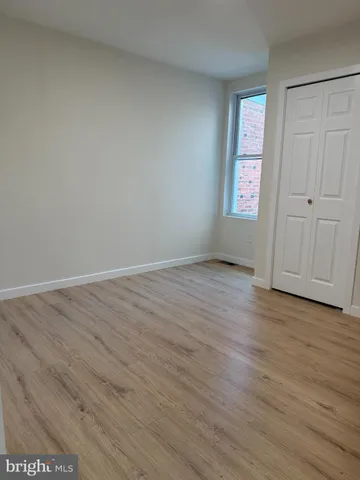 a view of an empty room with wooden floor and closet area