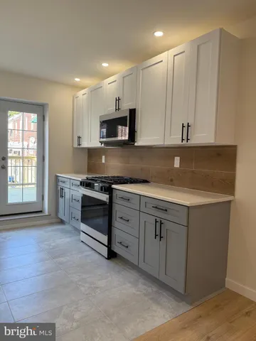 a kitchen with granite countertop white cabinets and stainless steel appliances