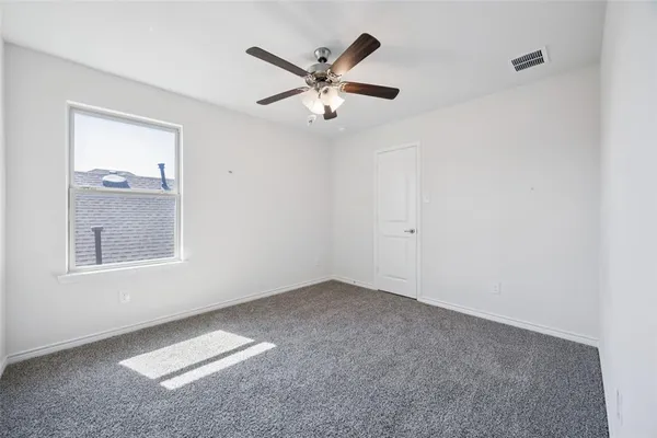 a view of an empty room with window and a ceiling fan