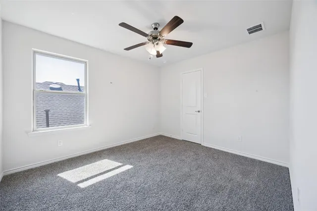 a view of an empty room with window and a ceiling fan