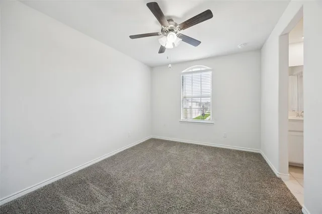 an empty room with ceiling fan and windows