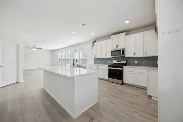 a kitchen with kitchen island granite countertop a sink a counter top space stainless steel appliances and cabinets