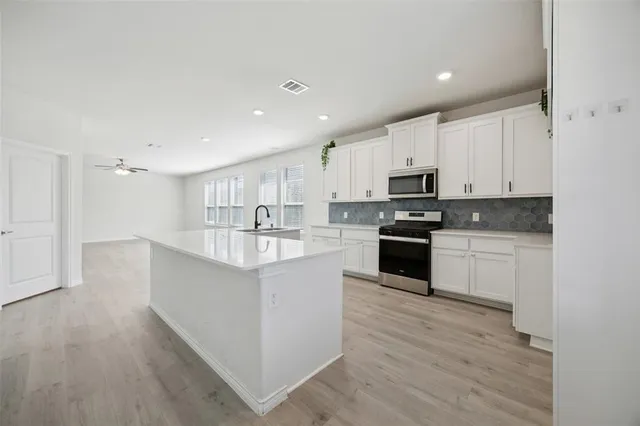 a kitchen with kitchen island granite countertop a sink a counter top space stainless steel appliances and cabinets
