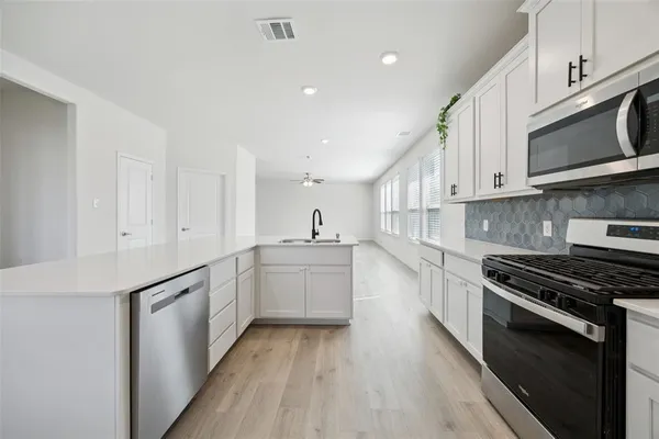 a kitchen with stainless steel appliances granite countertop a stove a sink and a microwave