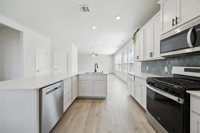 a kitchen with stainless steel appliances granite countertop a stove a sink and a microwave