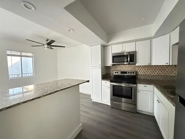 a kitchen with granite countertop a sink cabinets and stainless steel appliances