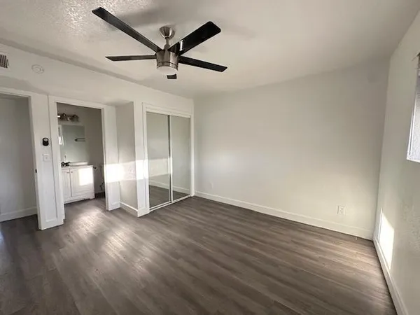 an empty room with wooden floor and ceiling fan