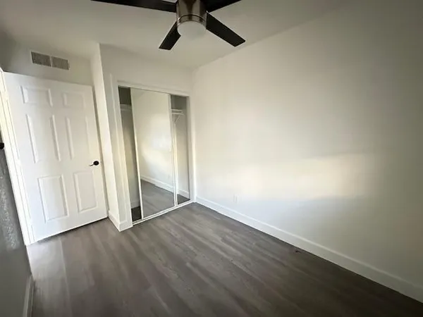 an empty room with wooden floor cabinet and windows