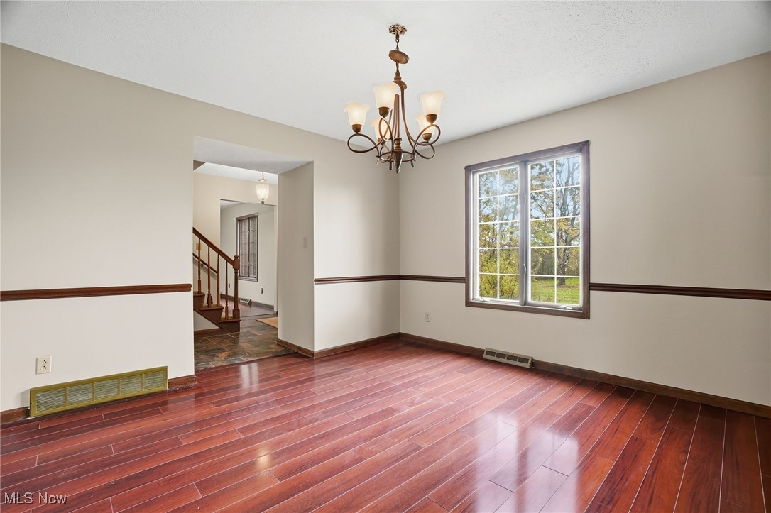 11710 Butternut Road Chardon, OH 44024 - Photo 16 of 48 Unfurnished room with dark wood-style floors, a chandelier, and stairs