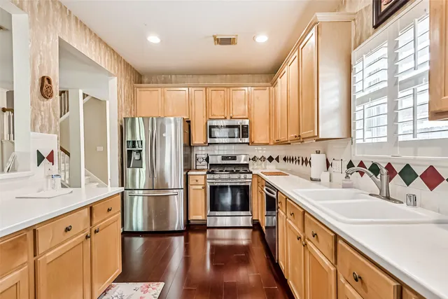 a kitchen with stainless steel appliances granite countertop a refrigerator a stove a sink and white cabinets with wooden floor