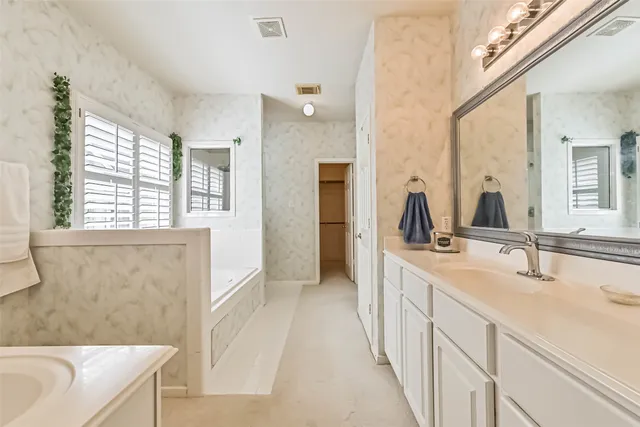 a en suite bathroom with a double vanity sink a mirror and a bathtub