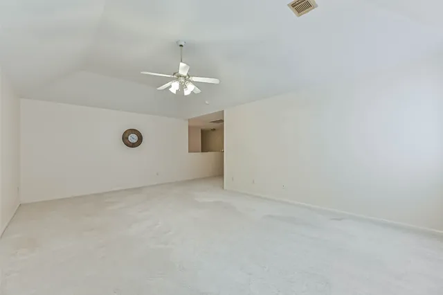 an empty room with a chandelier fan and windows