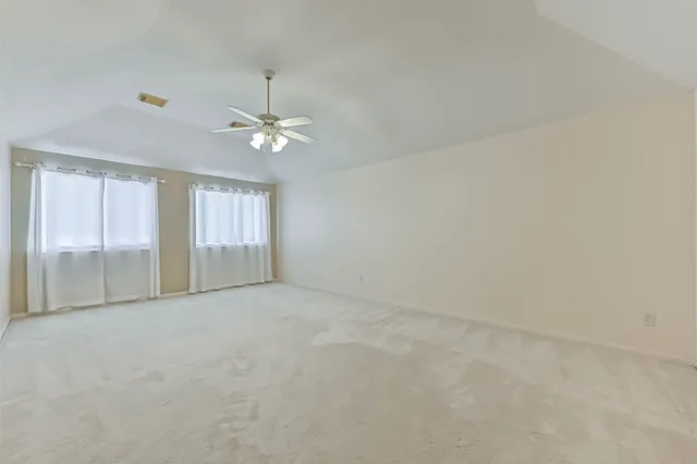 an empty room with chandelier fan and windows