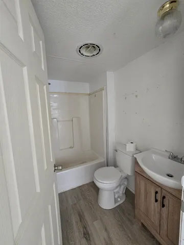 a bathroom with a sink a toilet a shower and a window