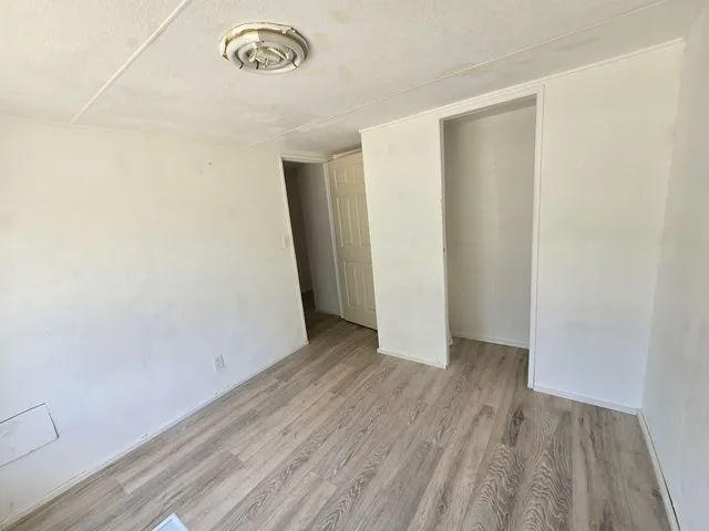 a view of an empty room with closet and a window