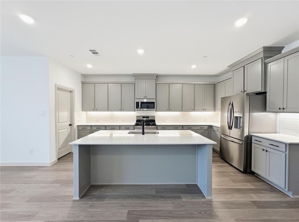2837 Bluejack Road McKinney, TX 75071 - Photo 11 of 40 a kitchen with stainless steel appliances kitchen island a sink and refrigerator